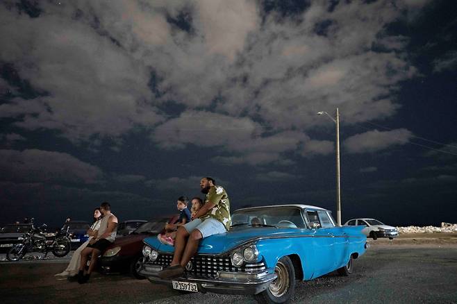 자영업자 빅토르 페레즈가  4월 13일 쿠바 아바나 해변의 무료 야외극장에서 아이들과 함께 자동차 보닛 위에 앉아 영화를 관람하고 있다./로이터 뉴스1