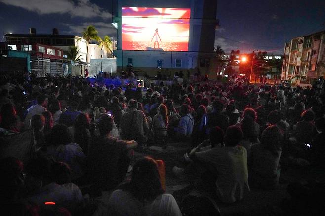 지난 4월 13일 쿠바 아바나의 해변가 주차장 야외 영화관에서 사람들이 영화를 관람하고 있다. 아파트 외벽이 스크린 역할을 하고 있다./로이터 뉴스1