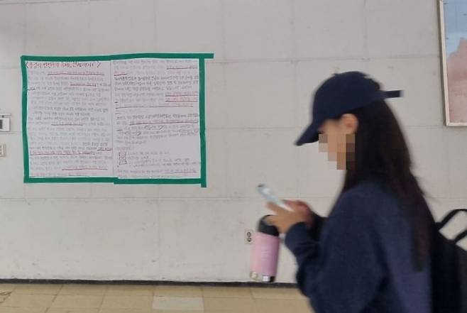 덕성여대 민주덕성 비상대책위원회에서 3월 학생회관 건물 벽 한쪽에 부착한 대자보 앞으로 한 학생이 지나가고 있다.[사진=심성아 기자]