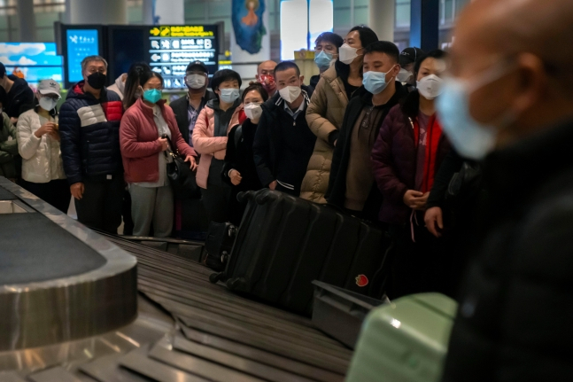 중국 베이징 서우두 국제공항에서 여행객들이 마스크를 쓰고 짐이 나오기를 기다리고 있다. [AP=연합]