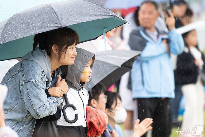 5일 구미 낙동강변체육공원에서 열린 구미시 어린이날 행사에서 한 어린이가 어머니가 씌워주는 우산속에서 공연을 바라보고 있다. (구미시 제공) 2024.5.5/뉴스1 ⓒ News1 정우용 기자