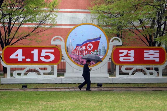 북한 최대 명절인 김일성 주석 생일(태양절)을 맞아 4월 15일 한 평양 시민이 태양절 경축 조형물 앞을 지나고 있다. 조형물엔 태양절 대신 '4.15'가 적혀있다. 평양=AP 뉴시스