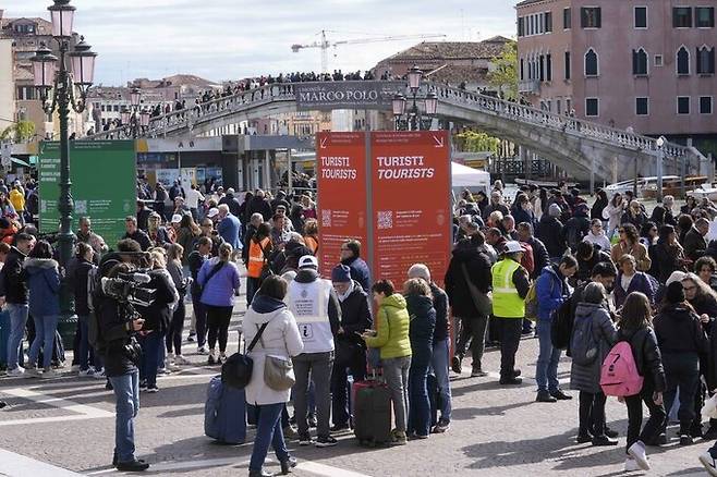 베네치아시 도로 위에 설치된 관광세 안내 표지판을 여행자들이 살펴보고 있다. AP연합뉴스