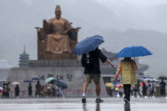 어린이 날을 맞은 5일 서울 종로구 광화문광장에서 우산을 쓴 가족 나들이객이 쏟아지는 빗속에 걸음을 옮기고 있다. 이날 광화문광장 '서울페스타 2024' 행사장 어린이 놀이시설은 비가 쏟아지는 날씨 때문에 취소 및 축소 운영됐다.    뉴스1