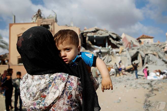 5일(현지시간) 가자지구 남부 라파에서 보호자 등에 업힌 한 어린이가 이스라엘의 주택 공습 현장을 바라보고 있다. 2024.05.05/ ⓒ 로이터=뉴스1 ⓒ News1 권진영 기자