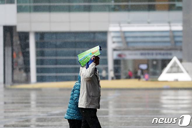 부산 해운대구 벡스코 광장에서 한 시민이 가방으로 비를 피하고 있다./뉴스1 ⓒ News1 윤일지 기자
