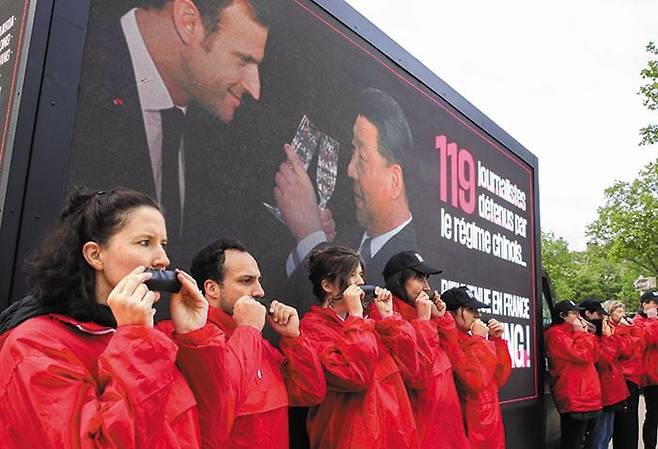 “中 억류 언론인 119명 석방하라” - 6일 프랑스 파리 에투알 개선문 인근에서 국경없는기자회 회원들이 ‘중국에 억류된 119명의 언론인을 석방하라’는 주장이 담긴 팻말과 함께 입에 검은 테이프를 붙이는 모습으로 시위하고 있다. 시진핑 중국 국가주석이 방문한 5일부터 파리 곳곳에서 반(反)중국 시위가 벌어졌다. /EPA 연합뉴스