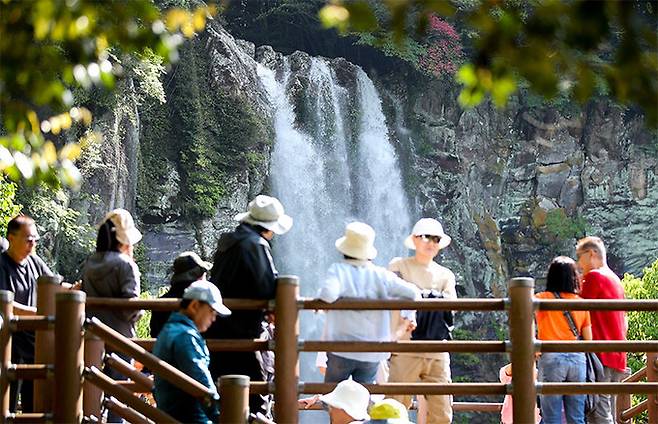 지난 6일 제주 서귀포시 강정동 엉또폭포를 찾은 관광객들이 절벽 아래로 떨어지는 시원한 물줄기를 감상하고 있다. 뉴시스