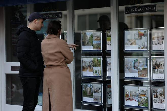 영국 런던의 한 거리에서 성인 남녀가 부동산 매물 정보를 살펴보고 있다./로이터 연합뉴스
