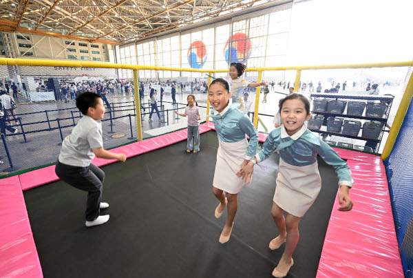 승무원 복장을 갖춰 입은 아이들은 테마파크로 변신한 격납고에 마련된 트램펄린 위에서 신나게 뛰어 놀고 있다.