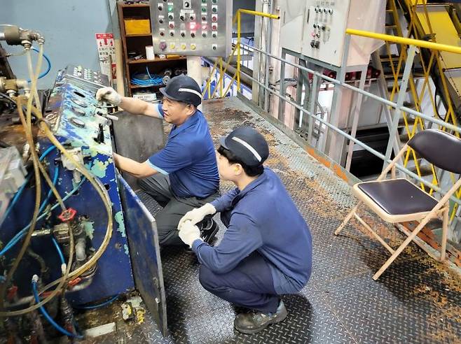 올해 휴비스 전주공장의 시니어인턴십에 채용된 김재석씨가 재생섬유 기계설비 유지보수 업무 노하우를 청년 멘티에게 전수해주고 있다. 사진제공=휴비스 전주공장