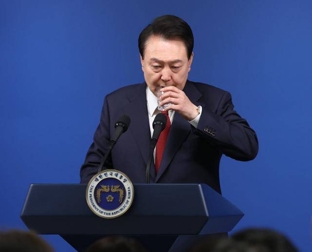 윤석열 대통령이 9일 서울 용산 대통령실 청사에서 열린 취임 2주년 기자회견에서 출입기자들의 질문을 들으며 목을 축이고 있다. 뉴시스