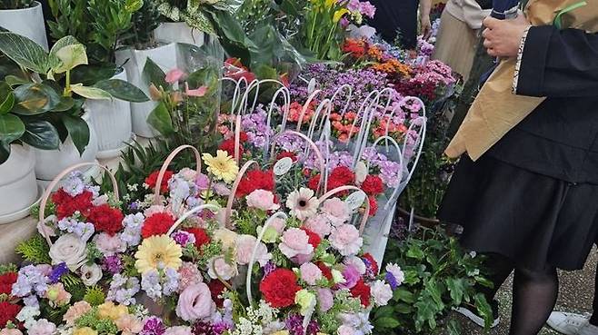 People look at baskets of carnations at a flower wholesaler in Namdaemun, central Seoul, a day ahead of Mother\'s Day, on May 7.