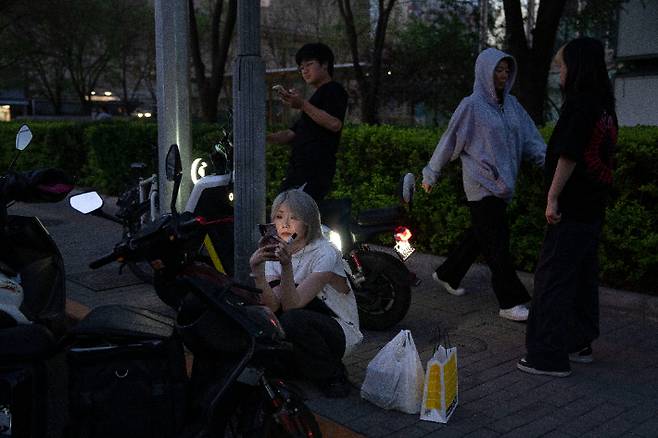 중국 베이징에서 휴대폰을 보고 있는 여성. 연합뉴스