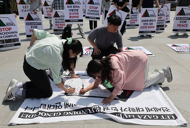 참여자들이 기자회견을 하기에 앞서 대학가 반전 시위 텐트 그림 위에 연대의 메시지를 적고 있다. 김영원 기자