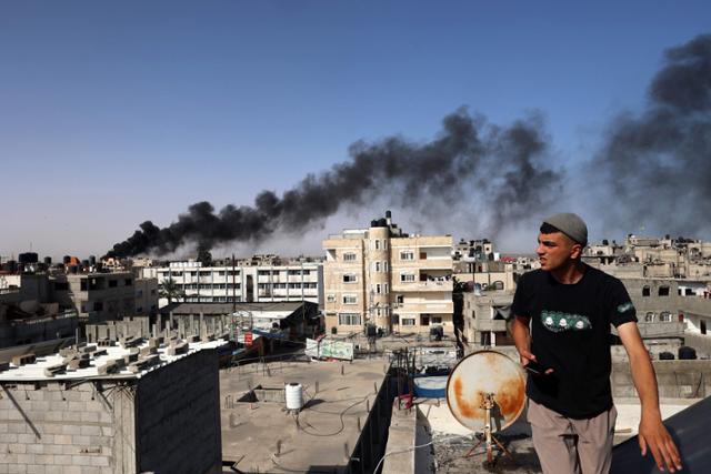 10일 가자지구 최남단 라파에서 한 남성이 이스라엘의 공습으로 검은 연기가 피어오르는 건물을 돌아보고 있다. 라파=AFP 연합뉴스