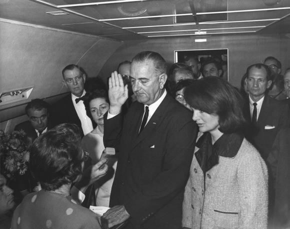 케네디 대통령이 암살된 직후 린든 존슨(가운데) 당시 부통령이 케네디의 아내 재클린(오른쪽)이 참석한 가운데 에어포스원에서 대통령직 승계 선서를 하고 있다.