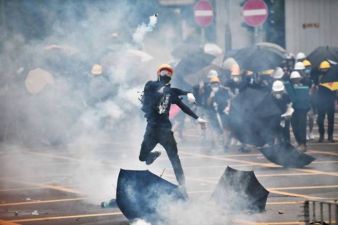 2019년 7월27일 홍콩 위안랑 지역에서 '백색테러' 규탄 시위가 벌어진 가운데 한 시위 참가자가 경찰이 쏜 최루탄을 되던지고 있다. [이미지출처=AFP연합뉴스]