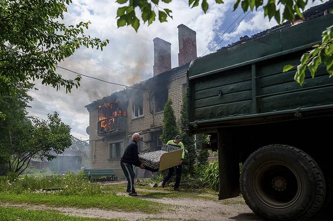 11일(현지시간) 우크라이나 동북부 보우찬스크에서 러시아군의 공격이 시작된 가운데 주민들이 불타고 있는 집에서 물건을 나르며 대피하고 있다. AP연합뉴스