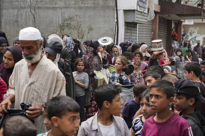 지난 10일(현지시각) 가자지구 데이르 알발라에서 식량을 배급받으려는 팔레스타인 난민들이 식기를 들고 순서를 기다리고 있다. /AP=뉴시스