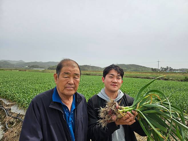 손재영 GS리테일 농산팀 구매 담당자(오른쪽)가 전남 고흥군의 한 마늘밭에서 농민과 함께 수확을 앞둔 마늘을 점검하고 있다. [GS25 제공]