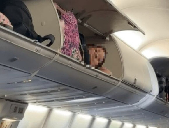 비행 중 여객기 내 좌석 위 짐칸에 들어가 잠을 청하는 ‘민폐 승객’의 모습이 포착돼 논란이 일고 있다. (사진=틱톡 캡처)