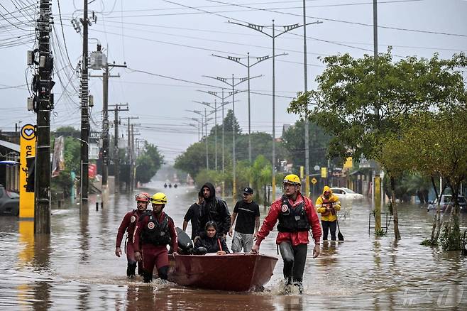 12일 (현지시간) 기록적인 폭우가 쏟아진 브라질 히우그란지두술주 상 레오폴두에서 소방대원이 보트로 주민을 대피시키고 있다. 2024.05.13 ⓒ AFP=뉴스1 ⓒ News1 우동명 기자