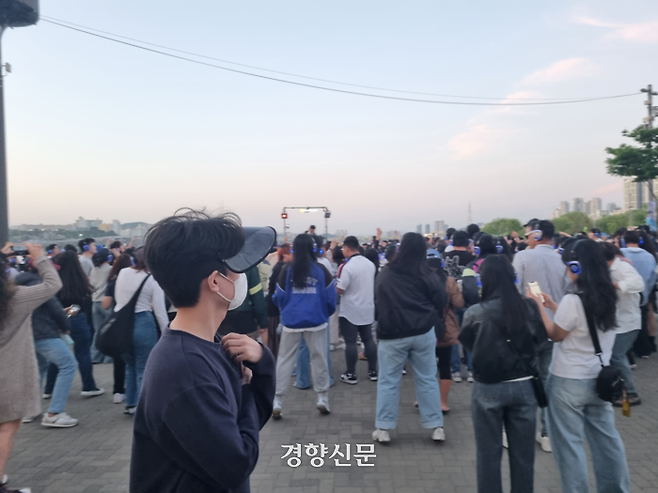 ‘한강무소음DJ파티’가 열린 12일 한 시민이 서울 서초구 반포한강공원 파티 현장과 참가자들을 보며 걸어가고 있다. 강한들 기자