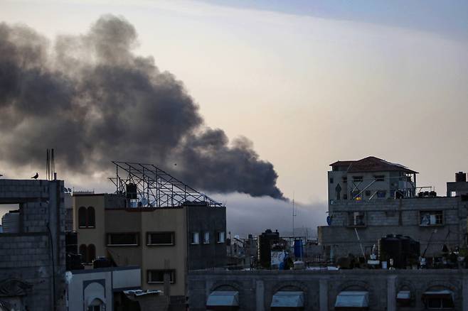 10일 동 트는 남부 가자 라파시 무너진 건물사이로 이스라엘군 포격에 당한 건물에서 뿜어져 나오는 검은 연기가 하늘을 덮고 있다. 이집트 중재로 진행되는 양측간 휴전 협상은 이날도 진전을 보지 못했다.  2024.05.10  /AFPBBNews=뉴스1