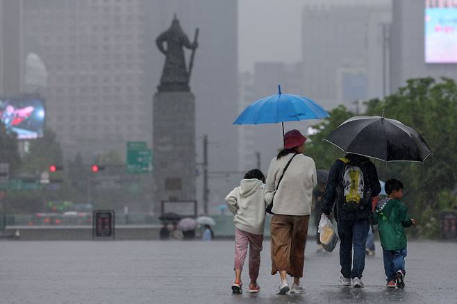 서울 종로구 광화문광장에서 우산을 쓴 가족 나들이객이 쏟아지는 빗속에 걸음을 옮기고 있다. /뉴스1