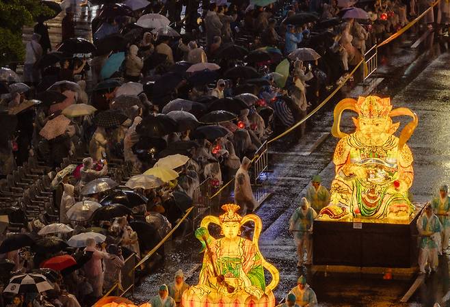 부처님오신날을 앞둔 11일 오후 서울 종로 일대에서 우산을 쓴 관람객들이 연등 행렬을 구경하고 있다. 뉴시스