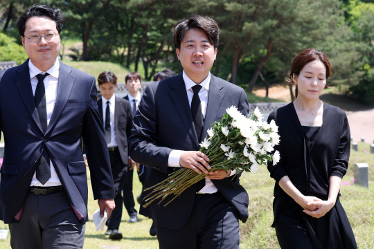 15일 오전 광주 북구 국립 5·18 민주묘지에서 개혁신당 이준석 대표와 당선인들이 국화를 들고 이동하고 있다. 이 대표는 경남 김해에서 재배한 국화 1천송이를 직접 공수해 995기에 달하는 개별 묘지에 헌화·참배했다.<연합뉴스>