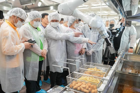 Superintendent Shin Kyoung-ho and event participants examine a frying robot during a demonstration and donation event held at Hansaem High School in Chuncheon, Gangwon, on April 29. [YONHAP NEWS]