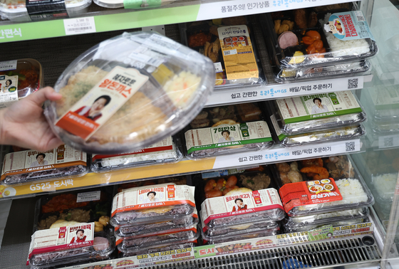 An employee at a convenience store in Seoul arranges lunch boxes on a shelf on Wednesday.[YONHAP]