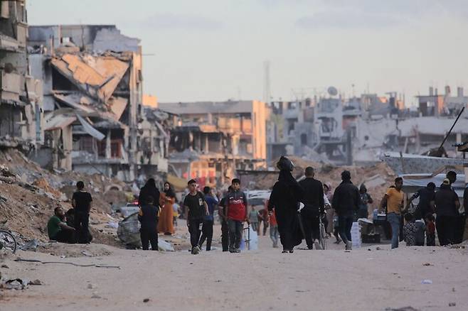 15일 팔레스타인인들이 이스라엘군의 폭격으로 황폐화된 가자지구 남부 칸유니스의 거리를 걷고 있다. 칸유니스/AFP 연합뉴스