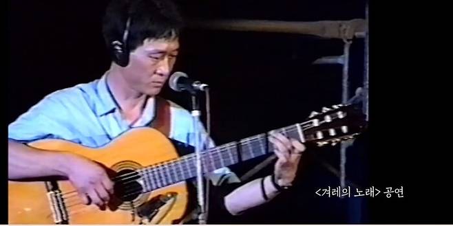 가수로서의 정체성을 거부하며 사석에서도 노래하지 않았던 김민기가 ‘겨레의 노래’ 공연에서 ‘아침이슬’을 부르고 있다. 프로그램 갈무리