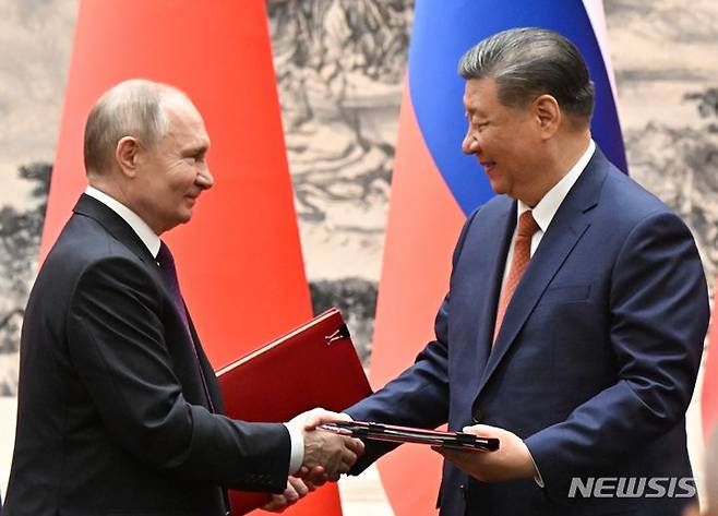 [베이징=AP/뉴시스] 블라디미르 푸틴(왼쪽) 러시아 대통령과 시진핑 중국 국가 주석이 16일 중국 베이징에서 회담 중 서명한 문서를 교환하면서 악수하고 있다. 2024.05.16.