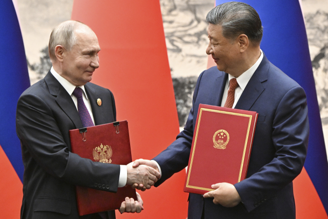 시진핑(오른쪽) 중국 국가주석과 블라디미르 푸틴 러시아 대통령이 16일 중국 베이징 인민대화당에서 열린 공동 서명식에서 협약서에 사인한 뒤 악수하고 있다. AP연합