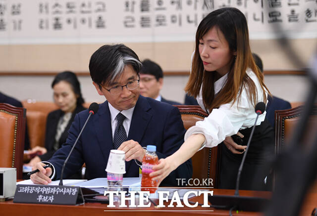오동운 공수처장 후보가 17일 서울 여의도 국회 법제사법위원회에서 열린 인사청문회에 출석한 가운데, 한 관계자가 빨간색의 음료를 건네고 있다.