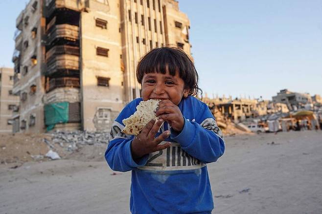 한 어린이가 16일(현지시각) 가자지구 남부 칸유니스에서 빵을 먹고 있다. AFP 연합뉴스