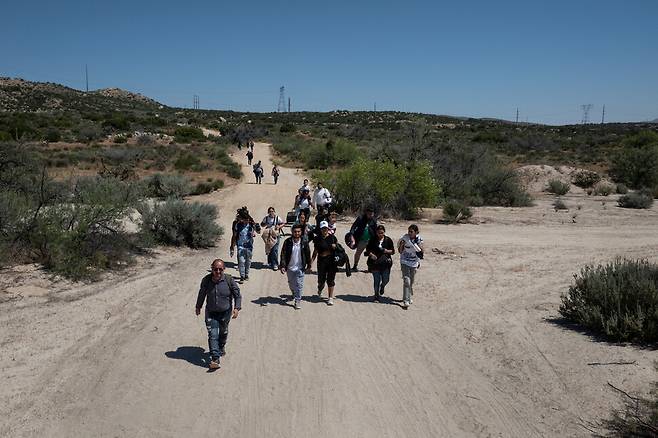 멕시코에서 미국으로 국경을 넘은 콜롬비아, 페루, 파나마에서 온 망명 신청 이민자들이 16일(현지시각) 미국 캘리포니아주 자쿰바 핫 스프링스에서 이민국 직원에게 자수하기 위해 걸어가고 있다. 로이터 연합뉴스