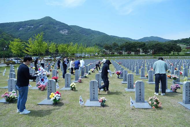 KINS 임직원들이 17일 대전 국립현충원 묘비에 태극기를 꽂고 있다.[KINS 제공]