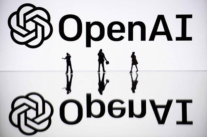 (FILES) This illustration photograph taken on October 30, 2023, in Mulhouse, eastern France, shows figurines next to a screen displaying a logo of OpenAI, a US artificial intelligence organisation. OpenAI on March 13, 2024 announced partnerships with French daily Le Monde and Spanish conglomerate Prisa Media, saying it intends to develop news-related uses of its ChatGPT artificial intelligence tool. OpenAI will be able to use content from Le Monde and Prisa Media publications including El Pais, Cinco Dias, and El Huffpost to train the models powering its artificial intelligence, the San Francisco-based company said in an online post. (Photo by SEBASTIEN BOZON / AFP)