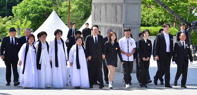 윤석열 대통령이 18일 오전 광주시 북구 운정동 국립5·18민주묘지에서 열린 제44주년 5·18민주화운동 기념식에서 5·18 유가족과 학생들의 손을 잡고 동반 입장하고 있다. ⓒ연합뉴스