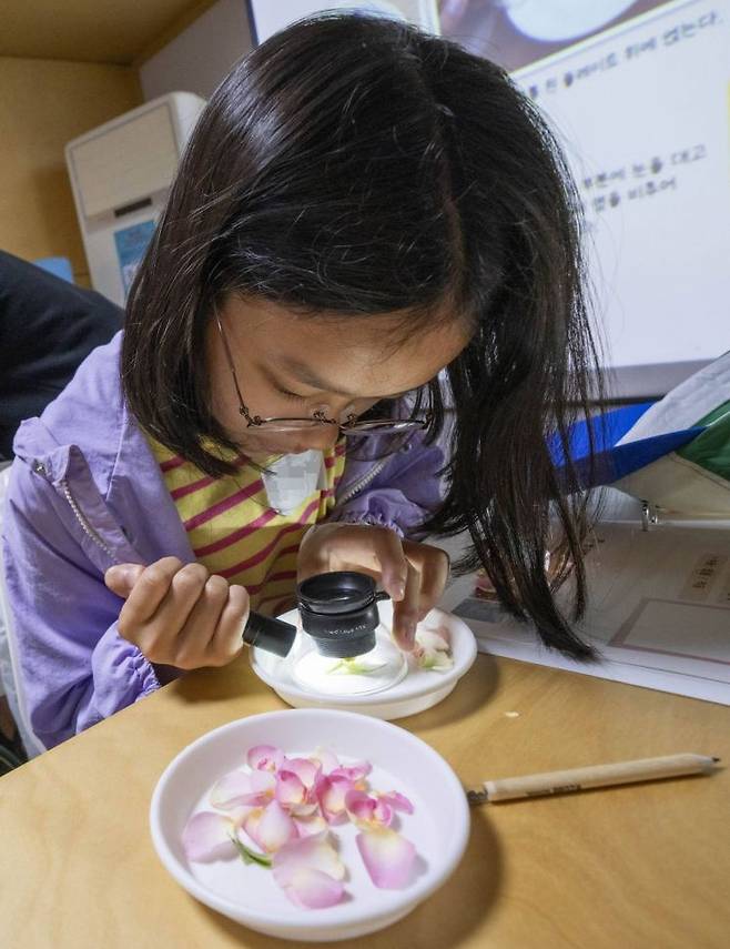 삼성 에버랜드 이큐브스쿨 참여 학생이 미니 현미경으로 장미를 관찰하고 있다. 사진=삼성물산 제공