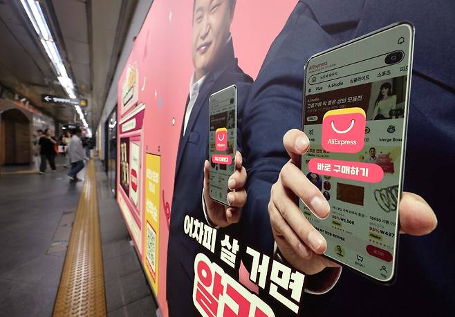 19일 정부가 국가인증통합마크(KC) 미인증 제품의 해외 직구를 금지한다는 방침을 사흘 만에 철회한 가운데 서울의 한 지하철역에 설치된 알리익스프레스 광고판 앞을 시민들이 지나가고 있다.  한주형 기자