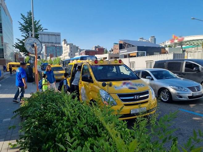 지난 14일 오후 4시30분께 서울 성북구 종암동의 한 초등학교 앞에서 학원 차량이 학생들을 태우고 있다. 어린이 통학버스 바로 옆 차선으로 자동차가 속도를 줄이지 않은 채 빠르게 지나가고 있다.[사진=심성아 기자]