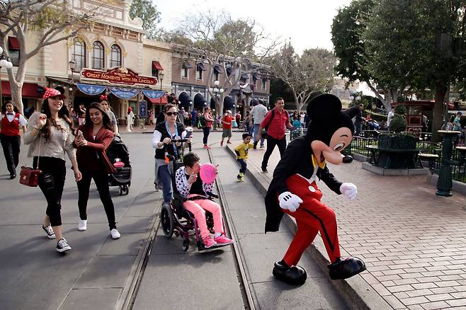 캘리포니아 디즈니랜드에서 미키마우스 탈을 쓴 직원이 관람객 앞을 걸어가고 있다. /AP 연합뉴스