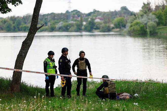 19일(현지시각) 러시아군의 미사일 공격을 당한 우크라이나 하르키우시 북부 호숫가 주변 휴식 공간에서 경찰들이 피해자를 확인하고 있다. 하르키우/로이터 연합뉴스