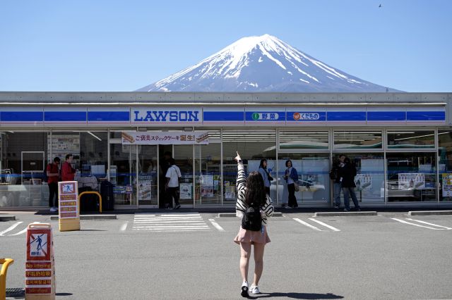 일본 후지산을 찍을 수 있는 사진 명소인 로손 편의점 앞에서 지난 10일 한 외국인 관광객이 자세를 취하고 있다. EPA연합뉴스